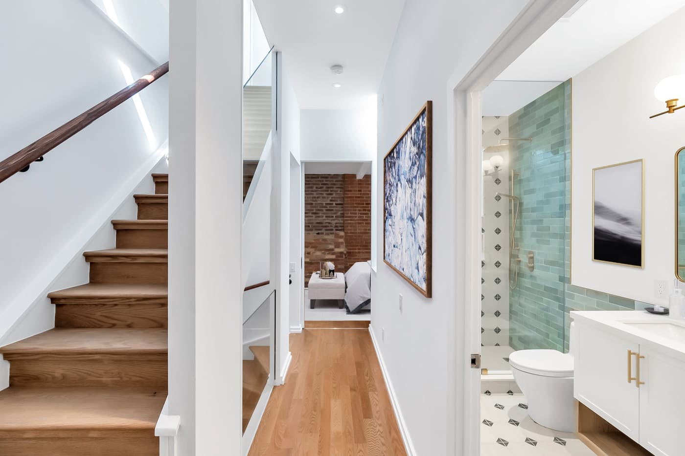 View of hallway in Toronto condo renovation with staircase and bathroom in shot