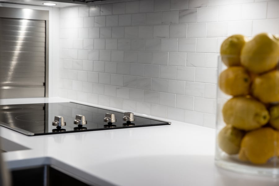 View of high-end cooktop with white subway backsplash and decorative lemons in Toronto Midtown small kitchen condo renovation