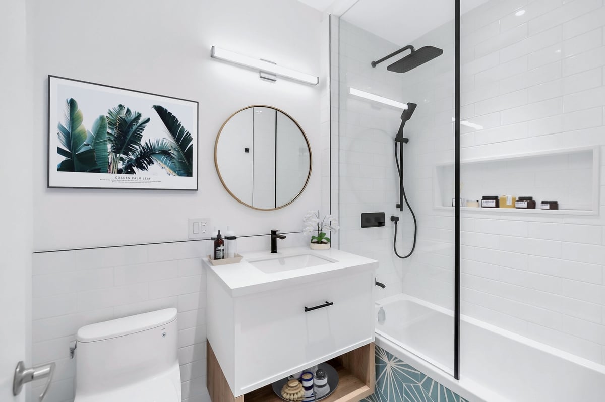 White condo bathroom renovation with black shower and faucet fixtures in Toronto