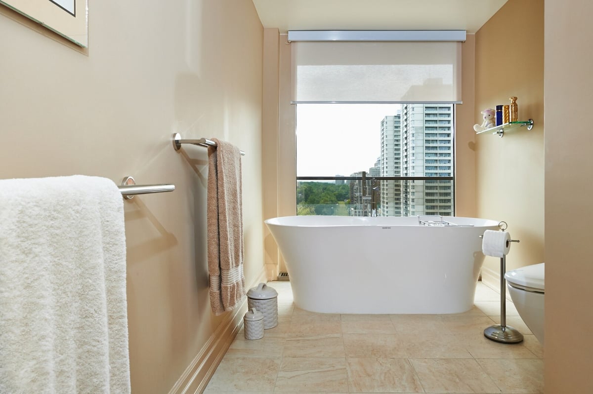 freestanding tub looking out window in bathroom renovation condo in toronto